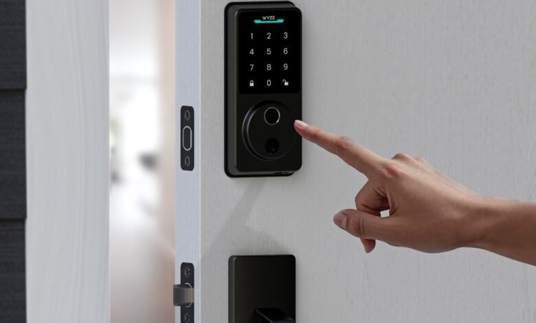 A finger presses the fingerprint scanner on a black Wyze smart lock.
