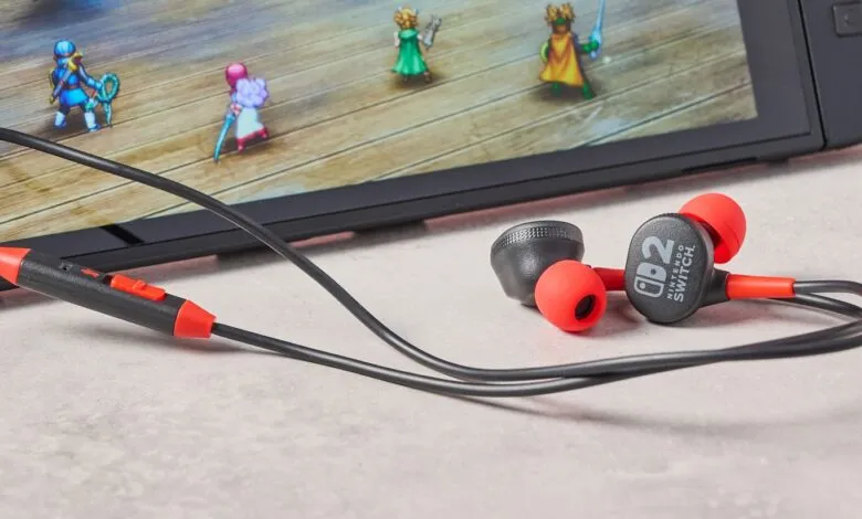 Nintendo Switch earphones with red earbuds and black cable next to a Switch console playing a game.
