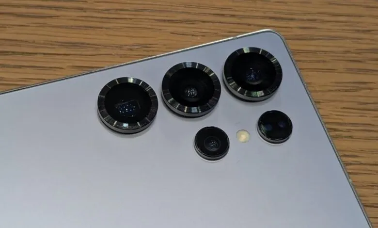 Close-up of a smartphone's rear camera array on a wooden surface.