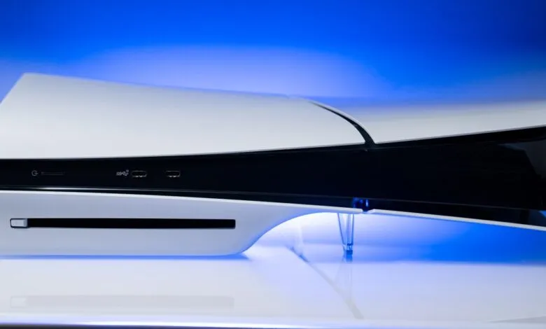 PlayStation 5 Slim console on a reflective white surface with blue lighting.