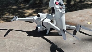 White drone and controller on a textured surface, casting shadows.