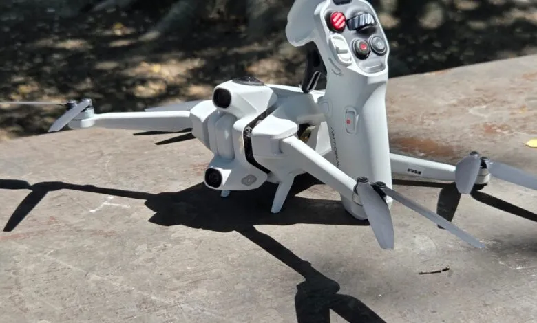White drone and controller on a textured surface, casting shadows.