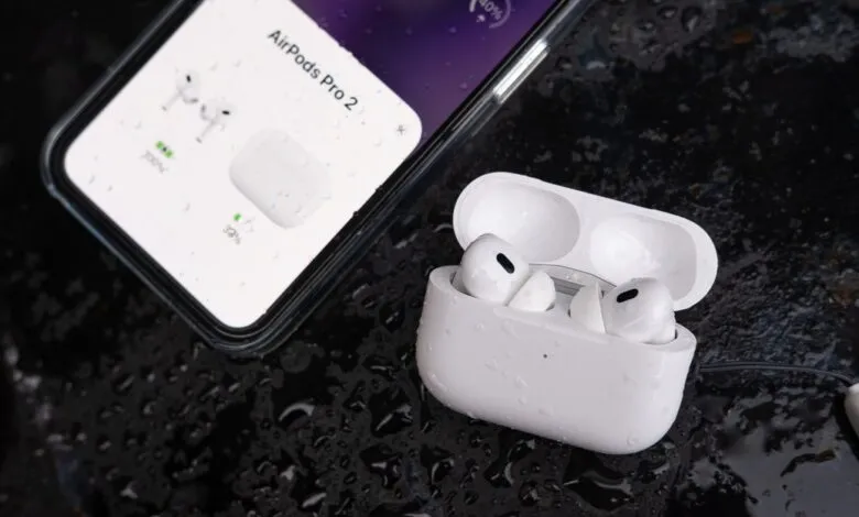 AirPods Pro 2 with charging case next to iPhone showing battery status.