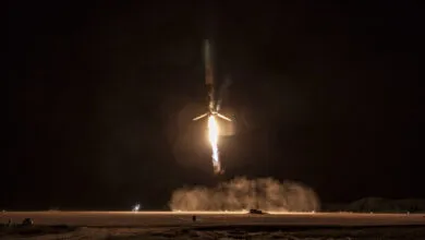 Rocket launches at night, flames and smoke visible against dark sky.