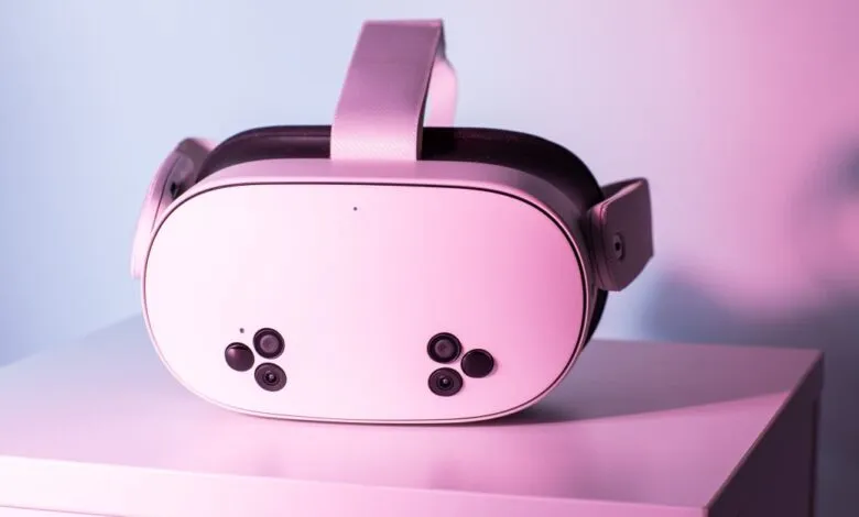 Meta Quest 3S VR headset on a white surface, lit with pink and blue.