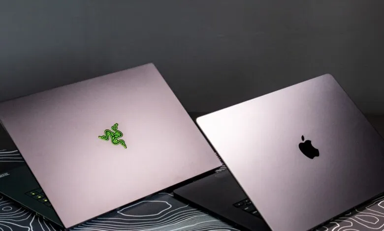 Razer Blade and Apple MacBook laptops side-by-side on patterned surface.