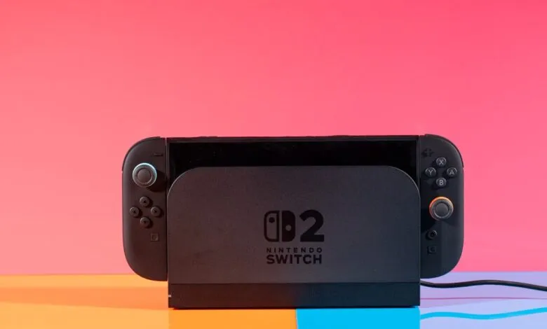 Nintendo Switch OLED model in dock, against a vibrant pink and blue background.