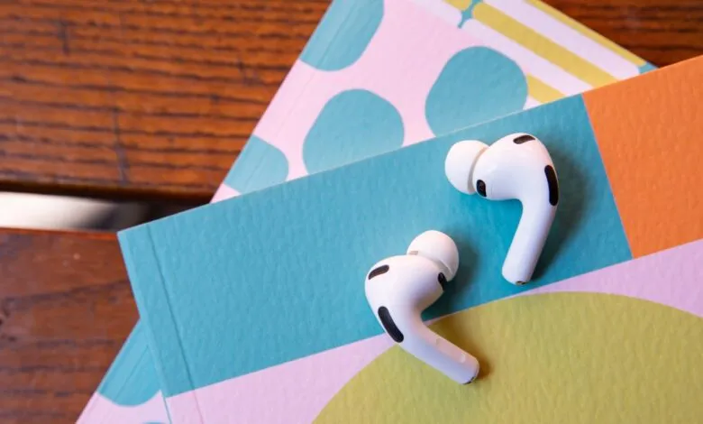 AirPods Pro earbuds on colorful patterned paper background.