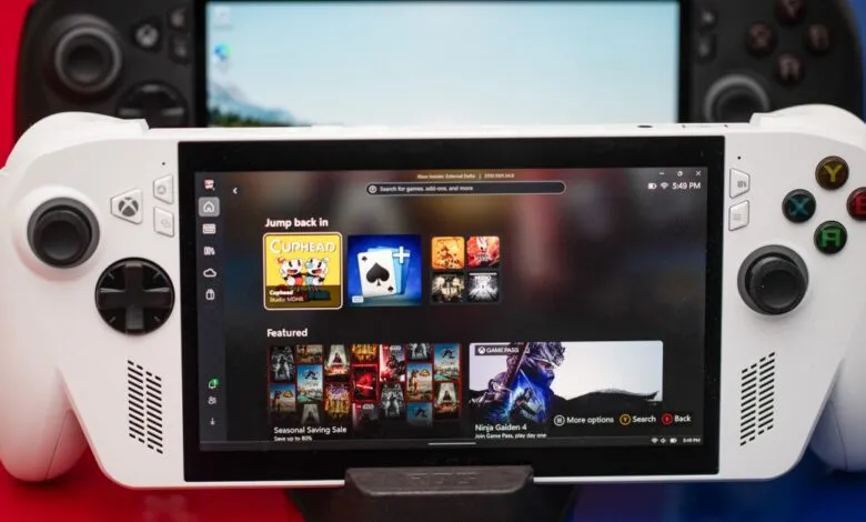 Close-up of white handheld gaming device displaying game menu with Cuphead icon.