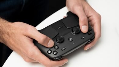 Hands holding a black Steam Deck controller against a white surface.
