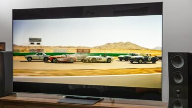 Large TV displaying vintage race cars on a wooden media console.