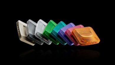 Row of colorful translucent Nintendo 64 consoles against a black background.