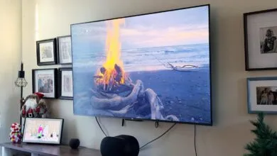 Large TV displaying beach bonfire scene, surrounded by family photos and holiday decor.
