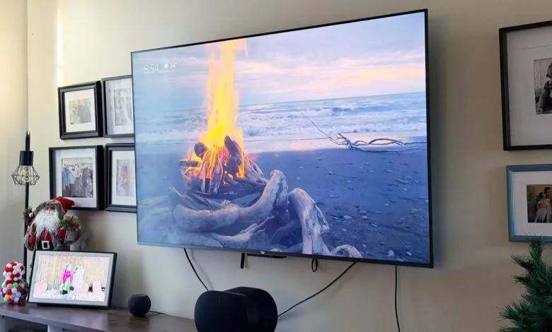 Large TV displaying beach bonfire scene, surrounded by family photos and holiday decor.