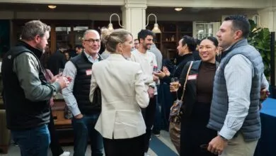 Group of people socializing at an indoor event, holding drinks and talking.