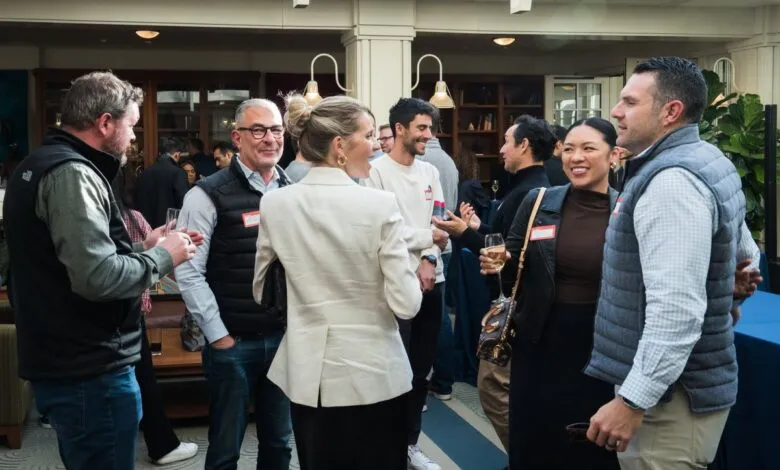 Group of people socializing at an indoor event, holding drinks and talking.