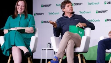 Two speakers sit on stage at TechCrunch Disrupt, one in green dress, one in navy sweater.