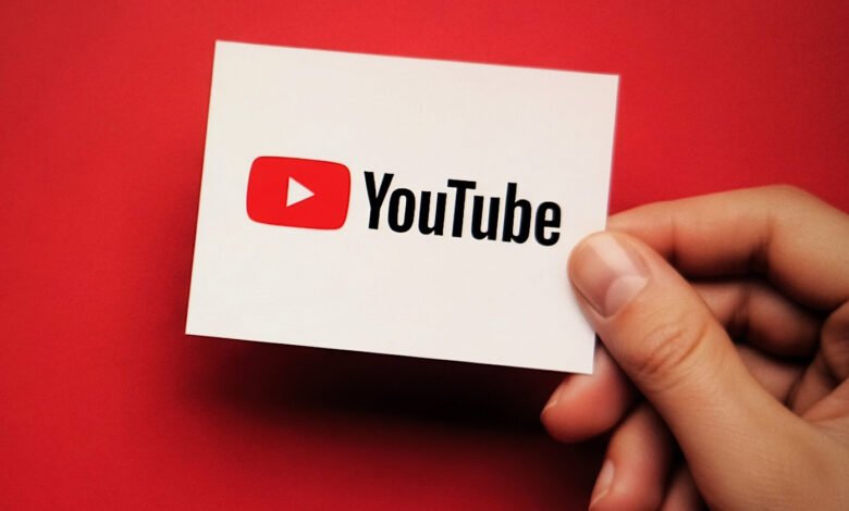 Hand holds a card with the YouTube logo against a red background.
