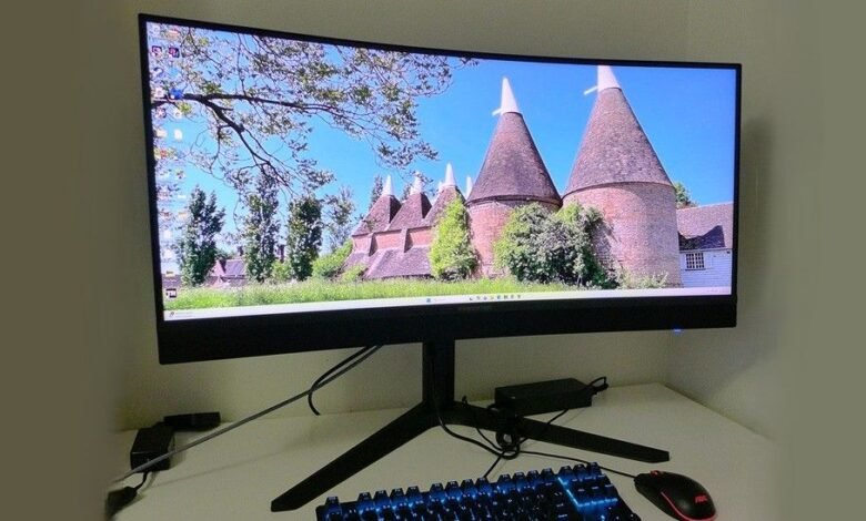 Curved monitor displays oast houses, keyboard and mouse visible.