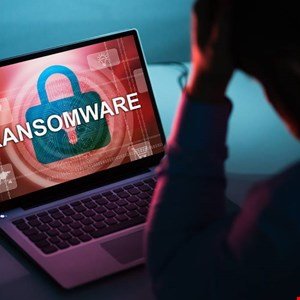 Laptop screen displays 'Ransomware' with a padlock, person in distress behind it.