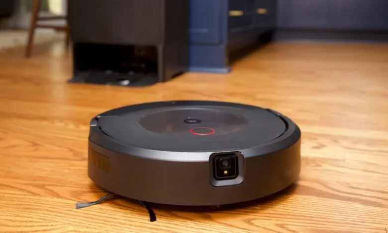 Black robot vacuum cleaner on hardwood floor with charging base.