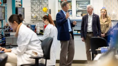 People in a lab setting, scientists working, others observing and discussing.
