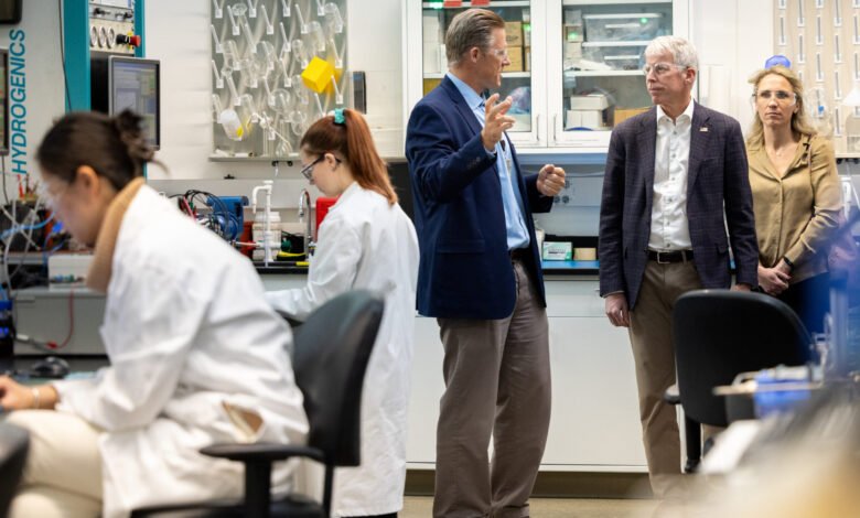 People in a lab setting, scientists working, others observing and discussing.