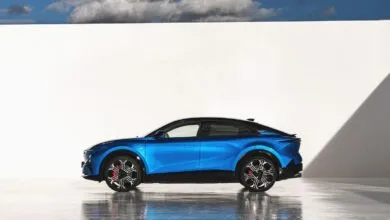 Side view of a blue Alpine A390 GT electric car against a white wall.