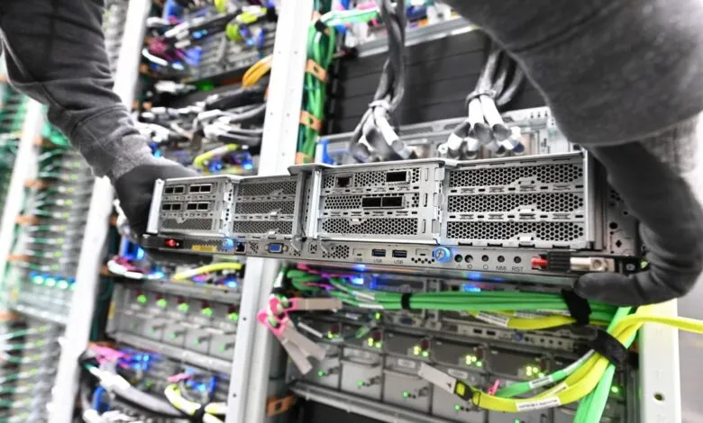 Technician installs server in data center rack with cables.