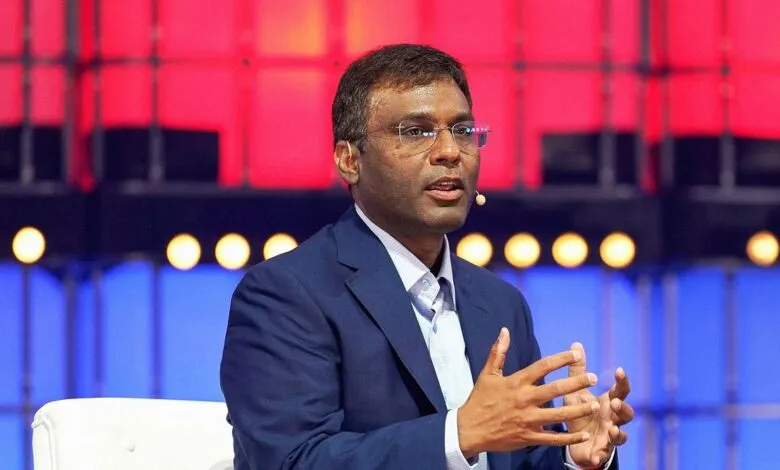 Rohan Patel speaking on stage, wearing a blue suit and glasses.
