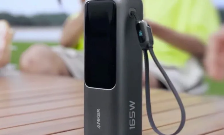 Anker 165W power bank on a wooden table with a person in the background.
