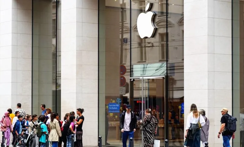 Apple store exterior with people walking and waiting outside the glass entrance.