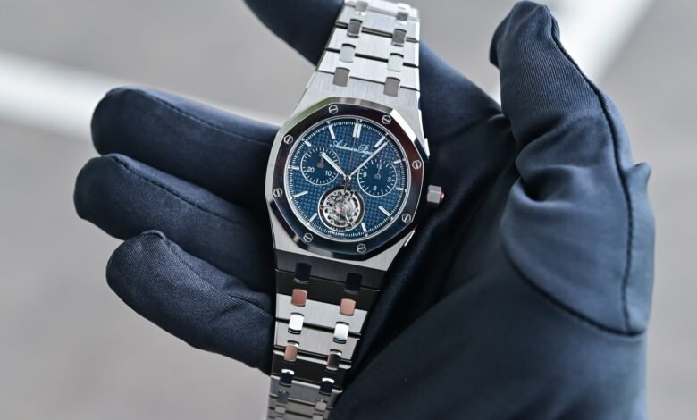 Audemars Piguet Royal Oak watch with a blue dial held in a gloved hand.