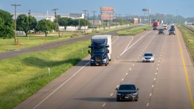 Highway with cars and a semi-truck on a sunny day.