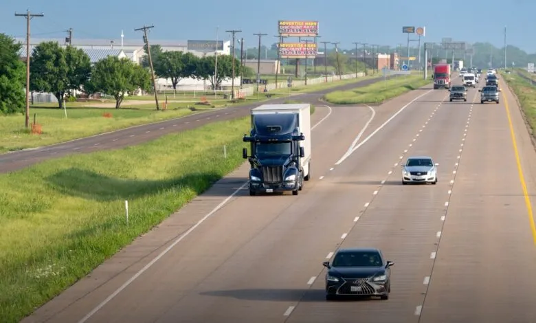 Highway with cars and a semi-truck on a sunny day.