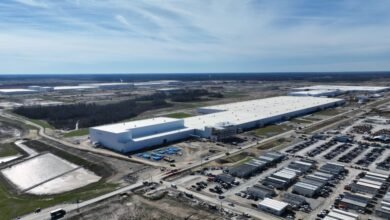 Aerial view of a large, modern industrial complex with white buildings and extensive parking.