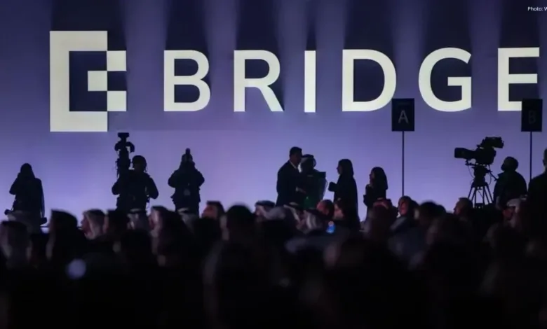 Audience at the Bridge event with stage and camera crew visible.