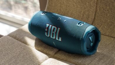 Blue JBL Charge speaker resting on a textured beige surface.