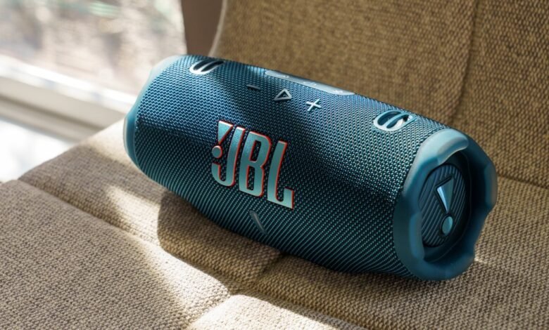 Blue JBL Charge speaker resting on a textured beige surface.