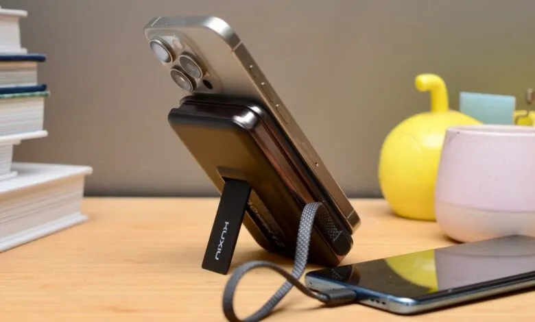 Silver iPhone attached to a black portable charger with a kickstand.