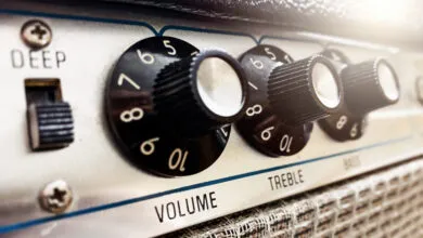 Close-up of a guitar amplifier with knobs for volume, treble, bass, and a deep switch.