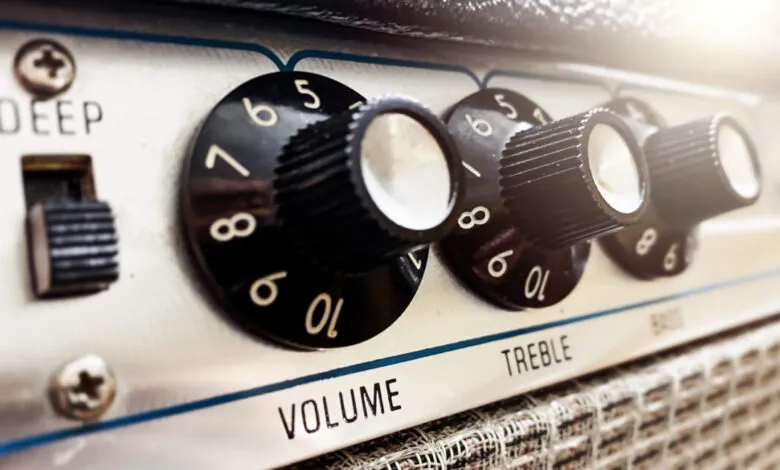 Close-up of a guitar amplifier with knobs for volume, treble, bass, and a deep switch.