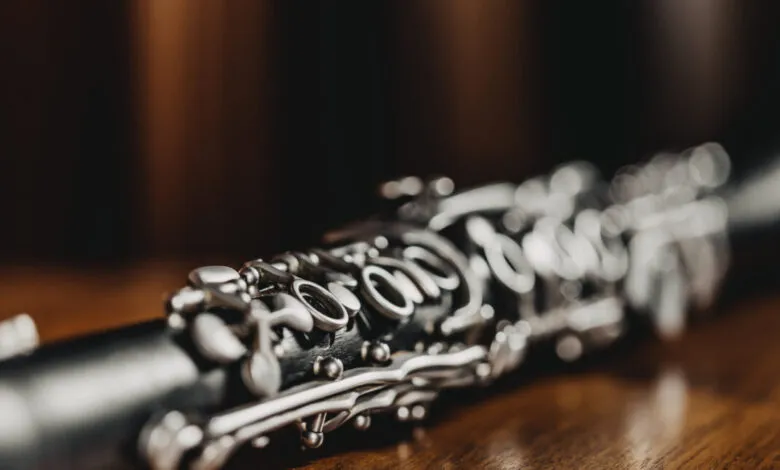 Close-up of a black clarinet with silver keys on a wooden surface.