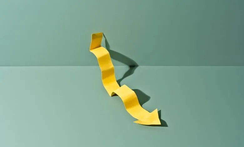 Yellow paper arrow pointing down on a green background.
