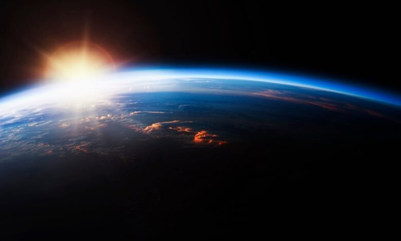 Earth from space with sunrise, showing atmosphere and cloud formations.