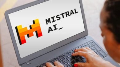 Laptop displaying Mistral AI logo with hands typing on the keyboard.