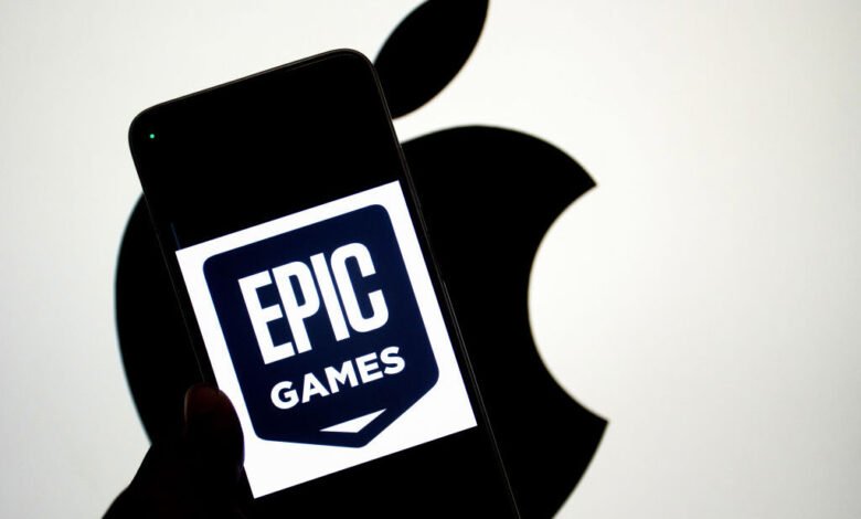 Epic Games logo on phone with Apple logo backdrop.
