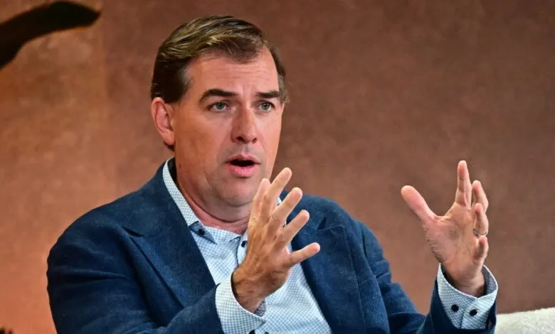 Man in blue blazer gestures during a discussion.