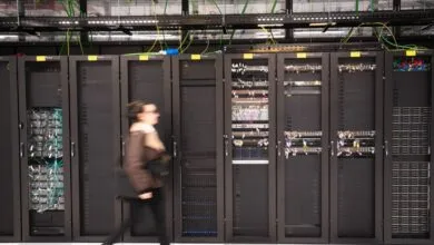 Woman walks past rows of server racks in a data center.