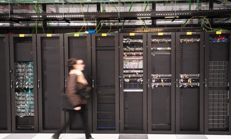 Woman walks past rows of server racks in a data center.
